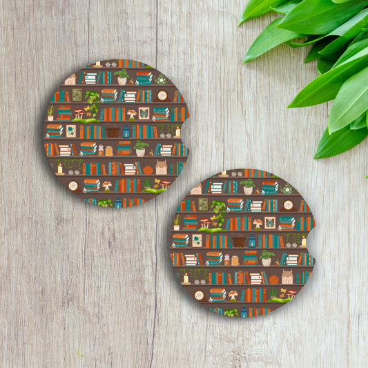 Two round coasters with book-themed design on a wooden surface with green leaves.