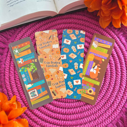 Colorful autumn-themed bookmarks on a pink woven mat with orange flowers and an open book.
