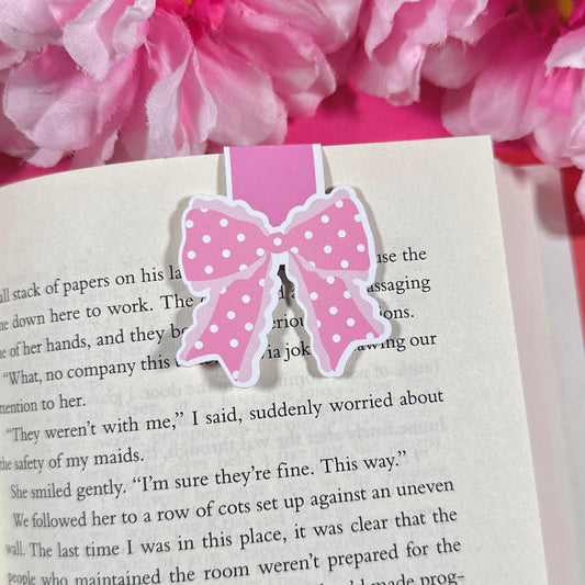 Pink polka dot bow bookmark on an open book with pink flowers in the background