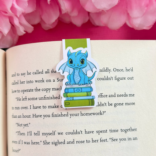 Magnetic bookmark with a blue and green dragon design on an open book surrounded by pink flowers