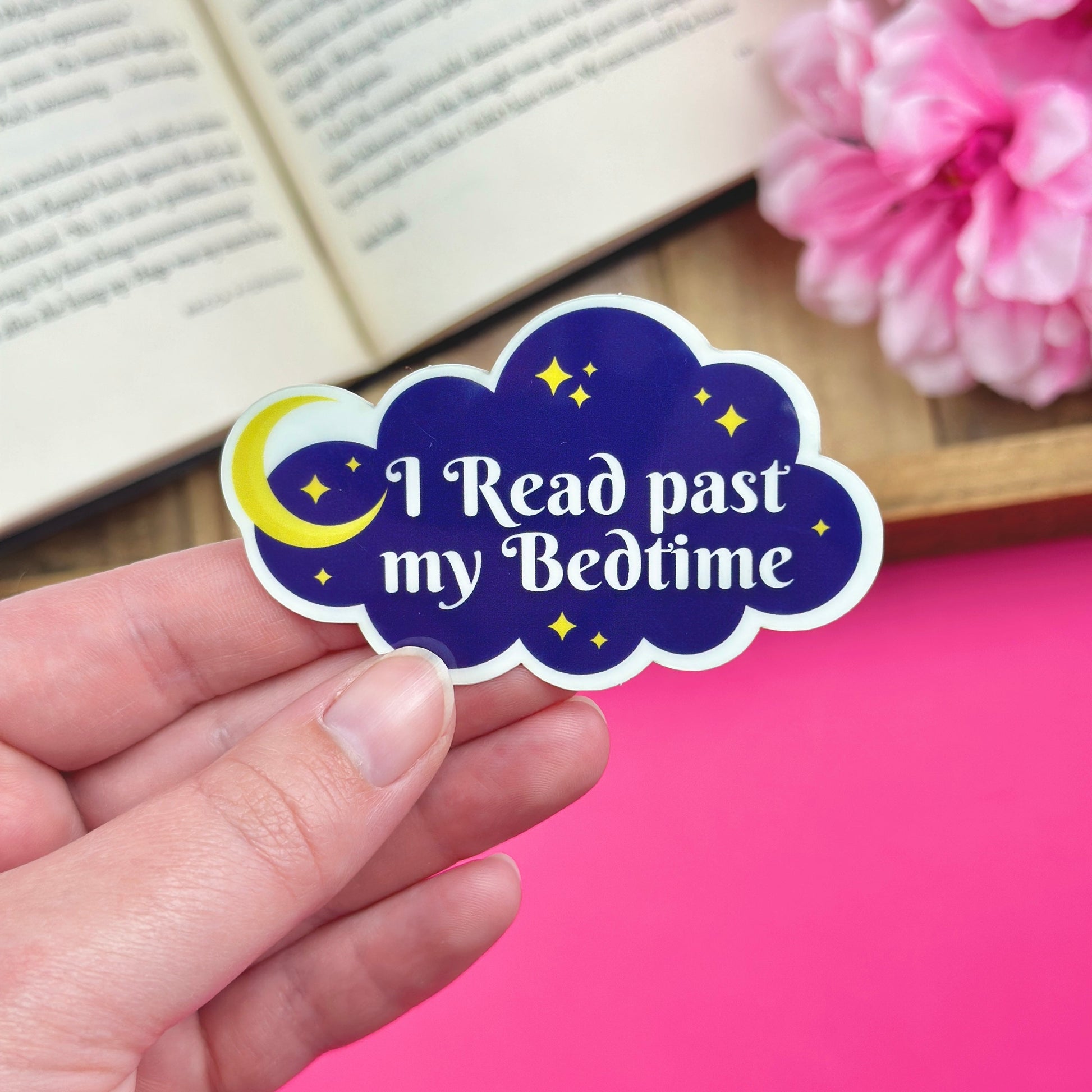 Sticker with 'I Read past my Bedtime' text held by a hand, with flowers and an open book in the background.